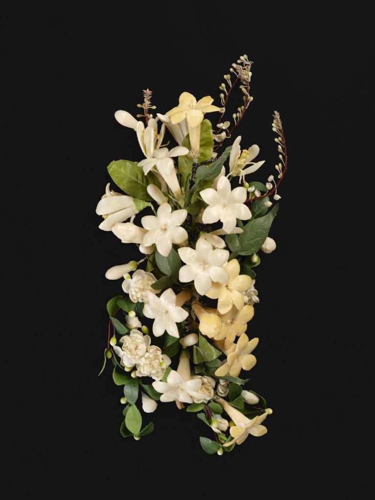 Broche en forme de bouquet de fleurs, avec de nombreuses fleurs blanches mélangées à des feuilles vertes et des gouttes nacrées.
