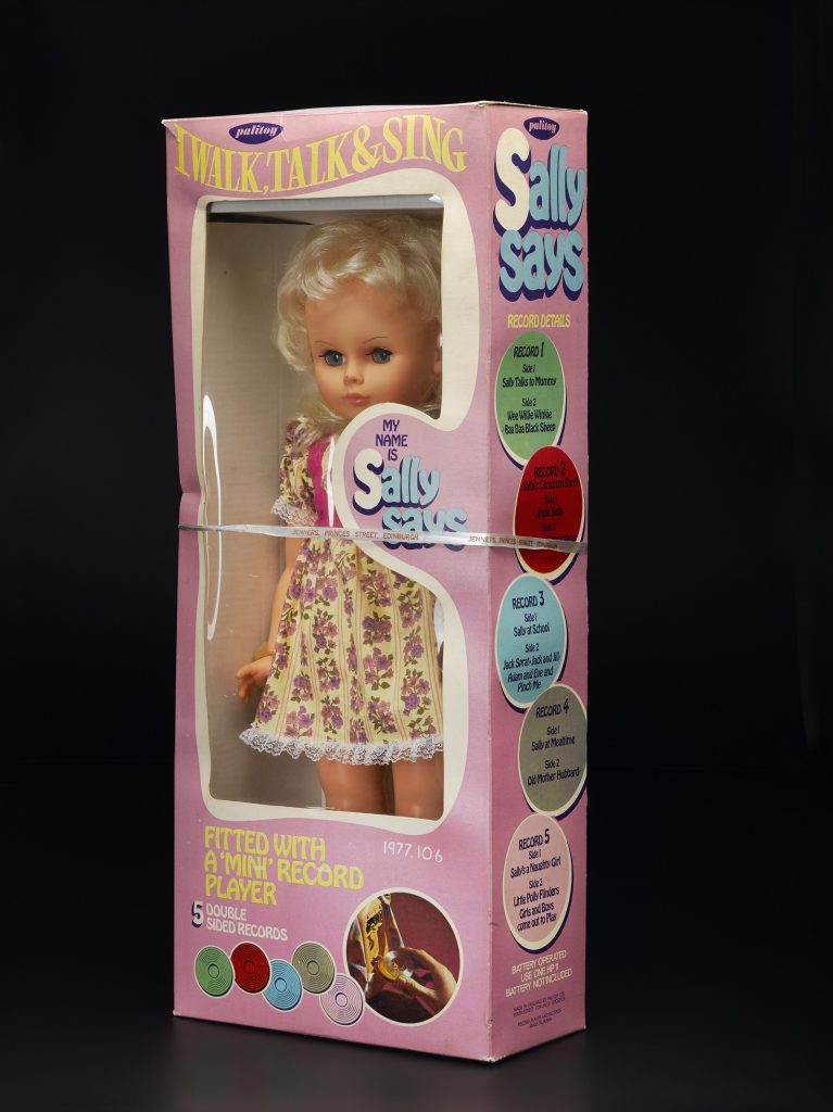 Une poupée 'Sally Says', blonde avec une robe à fleurs, toujours dans sa boîte de vente au détail.  La boîte se vante, 